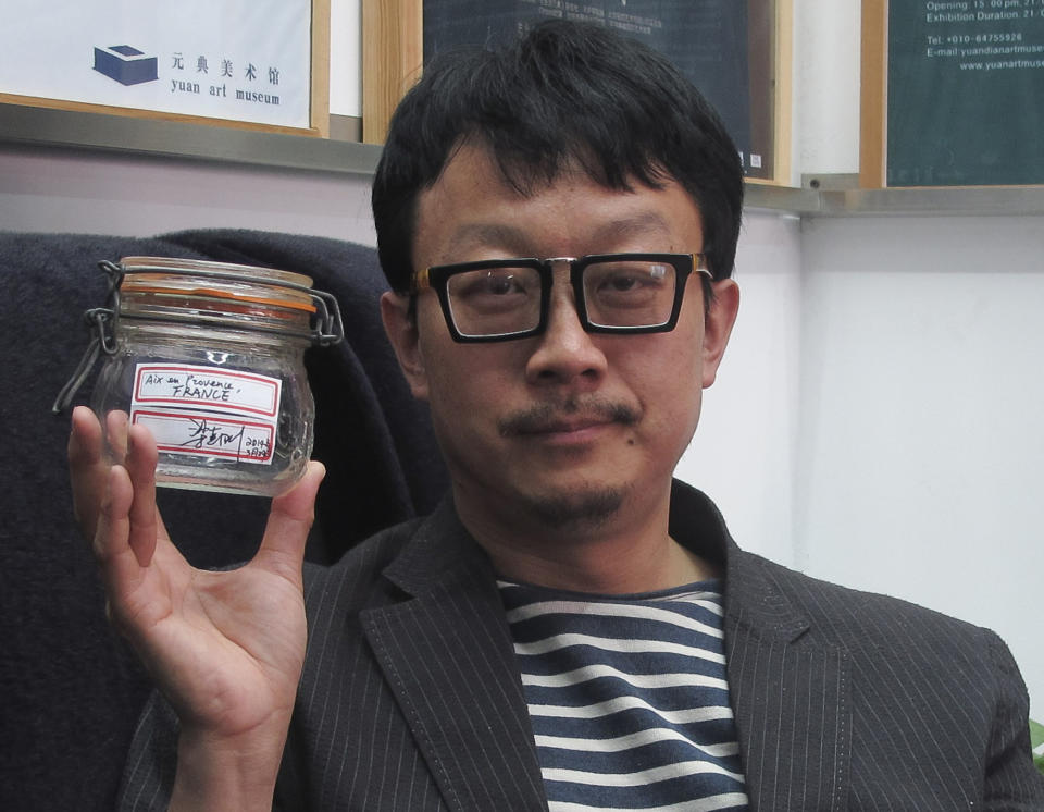 In this April 5, 2014 photo, Beijing artist Liang Kegang poses with the jar of fresh air collected in Provence, France, in an art gallery in Beijing, China. The jar of air has fetched $860 in a small auction as a piece of conceptual art to protest Beijing's choking pollution. (AP Photo/Didi Tang)