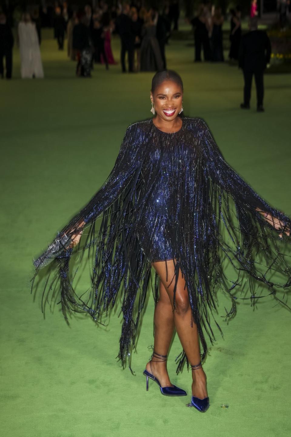 A woman in a sparkly blue dress posing on the green carpet