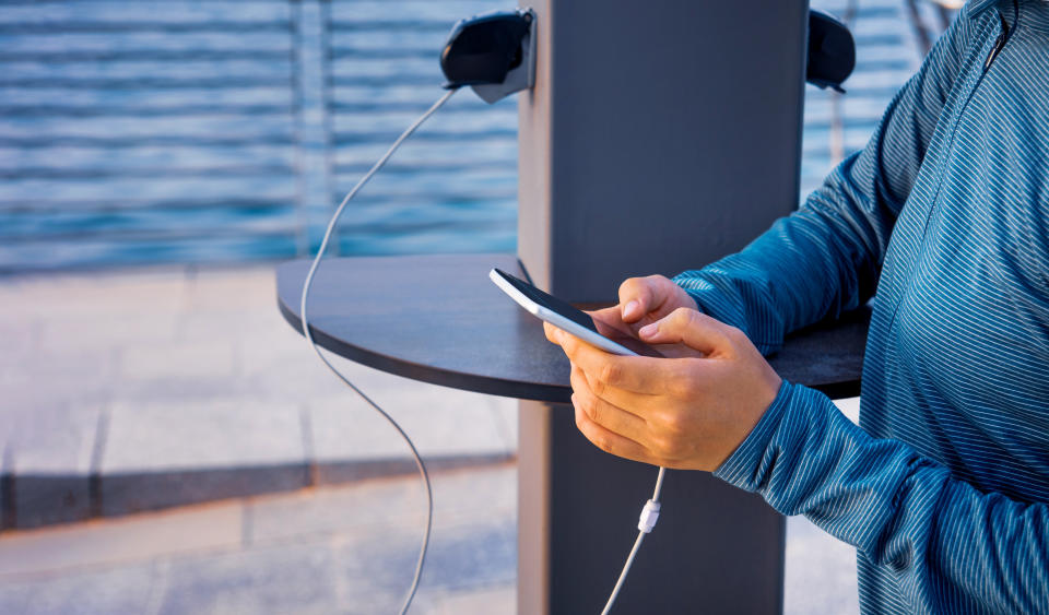 Female using phone and charging on a public charger