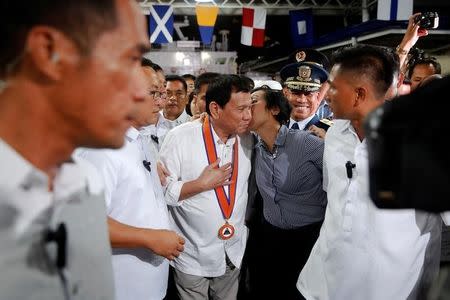 Philippines President Rodrigo Duterte is kissed by a woman as he attends the ceremony marking the anniversary of the Philippines Coast Guard in Manila, Philippines, October 12, 2016. REUTERS/Damir Sagolj TPX IMAGES OF THE DAY -