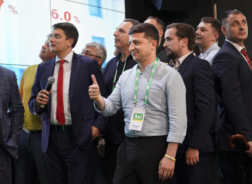 Ukrainian President Volodymyr Zelenskiy, center, reacts with his team as they look at the election results at his party's headquarters after a parliamentary election in Kiev, Ukraine, Sunday, July 21, 2019. Zelenskiy's party took the largest share of votes in the country's snap parliamentary election, an exit poll showed Sunday. (AP Photo/Evgeniy Maloletka)