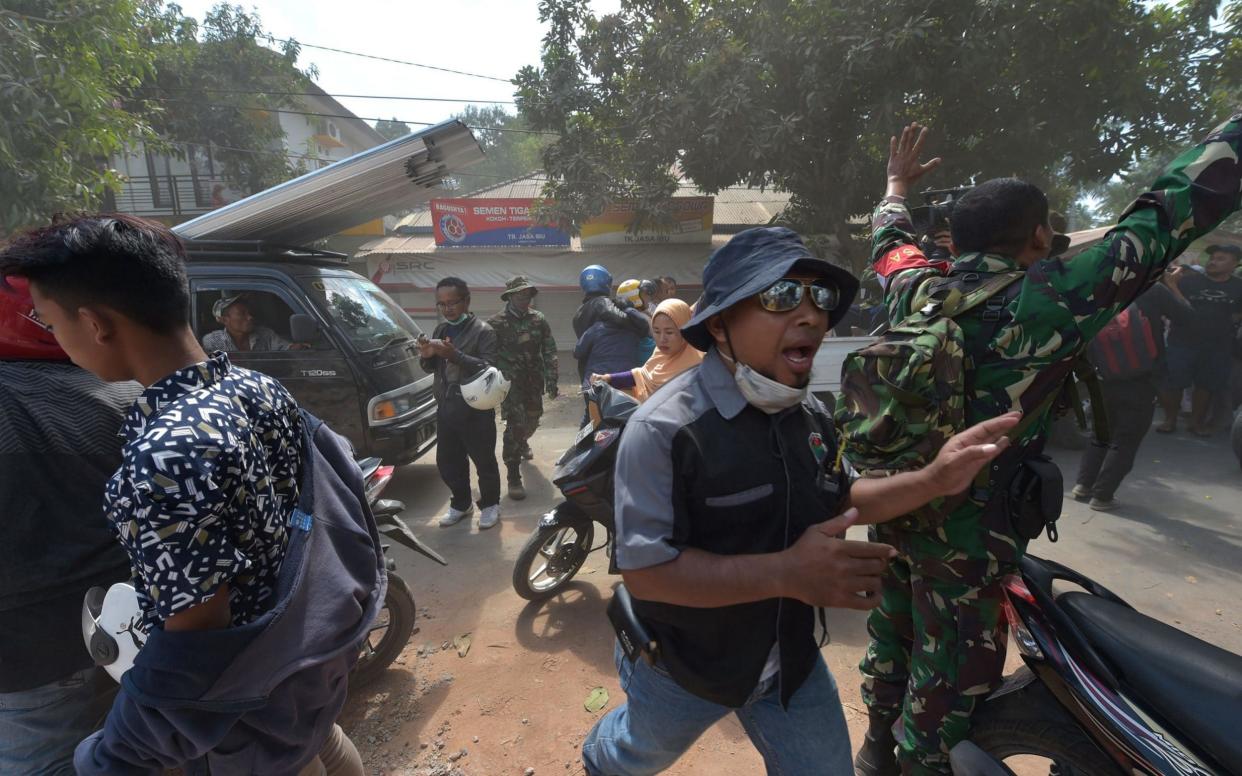 An Indonesian soldier and an official try to calm people shortly after an aftershock hits the area in Tanjung on Lombok island on August 9  - AFP