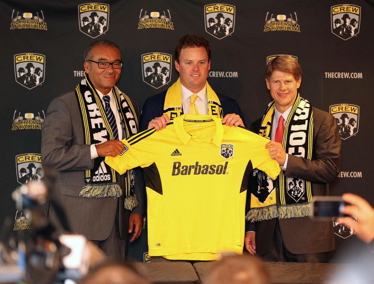 Anthony Precourt, center, new Chairman of the Crew along with Columbus Mayor Michael B. Coleman, left, and Clark Hunt, right, Chairman of Hunt Sports Group hold up a Columbus Crew jersey after The Crew and Hunt Sports Group announced today that Precourt Sports Ventures, LLC has acquired the operating rights to the Crew Crew Stadium in Columbus on July 30, 2013. (Dispatch photo by Kyle Robertson)