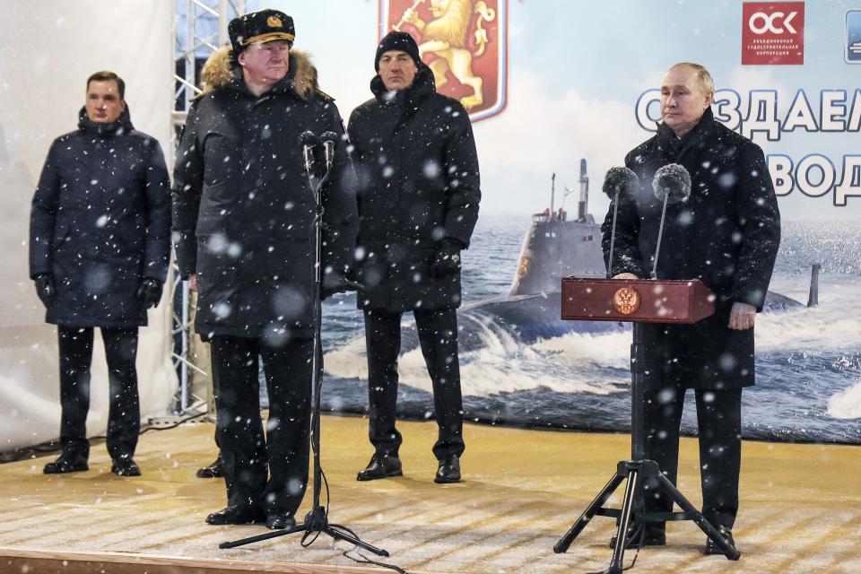 Russian President Vladimir Putin, right, delivers his speech as Admiral Nikolai Yevmenov, Commander-in-Chief of the Russian Navy, foreground left, listens to him during a flag-raising ceremony for newly-built nuclear submarines at the Sevmash shipyard in Severodvinsk in Russia's Archangelsk region, Monday, Dec. 11, 2023. The navy flag was raised on the Emperor Alexander III and the Krasnoyarsk submarines during Monday's ceremony. Putin has traveled to a northern shipyard to attend the commissioning of new nuclear submarines, a visit that showcases the country's nuclear might amid the fighting in Ukraine. (Kirill Iodas, Sputnik, Kremlin Pool Photo via AP)
