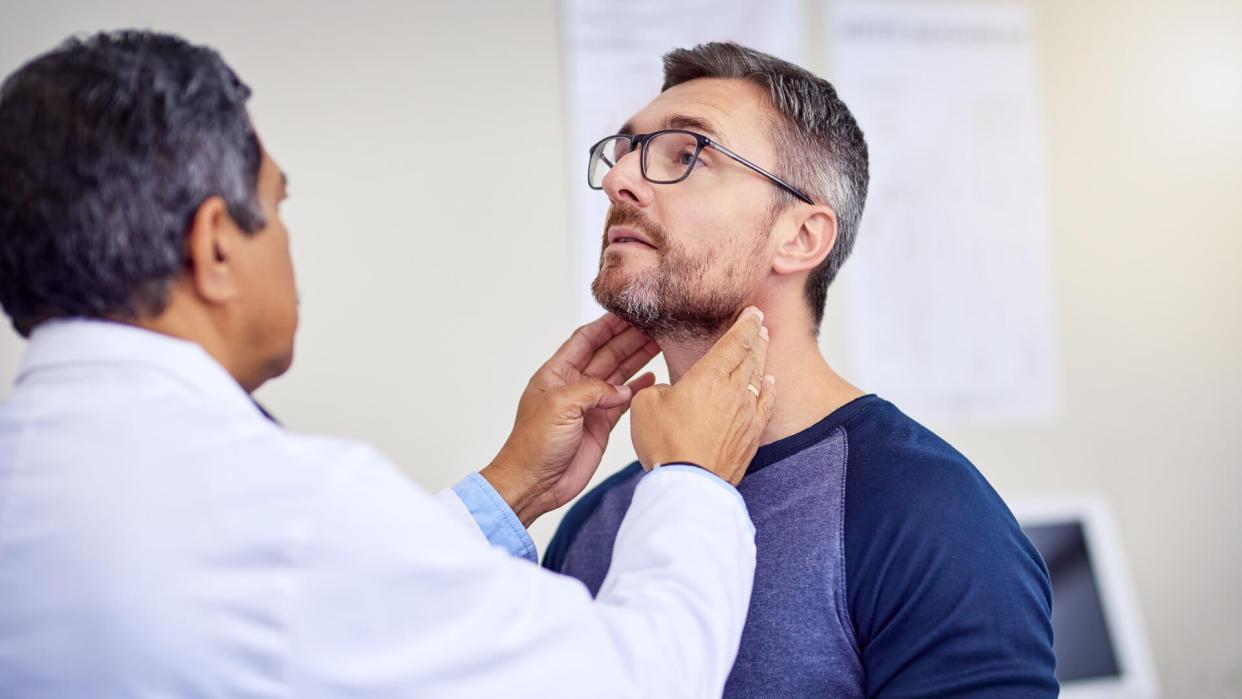 Shot of a confident mature male doctor doing a checkup on a patient while standing inside of a hospital during the day.