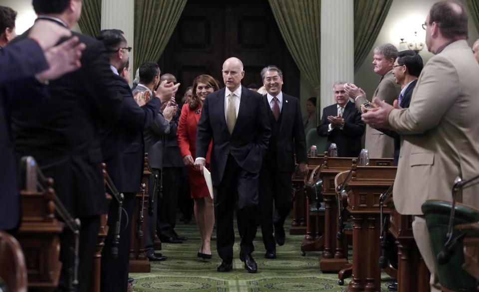 Gov. Jerry Brown receives applause from lawmakers as he walks to podium of the Assembly chambers to deliver his State of the State address at the Capitol in Sacramento, Calif., Wednesday, Jan. 22, 2014. Brown delivered a dual message in his annual address to the Legislature, that a California resurgence is well underway but is threatened by economic and environmental uncertainties.(AP Photo/Rich Pedroncelli, pool)