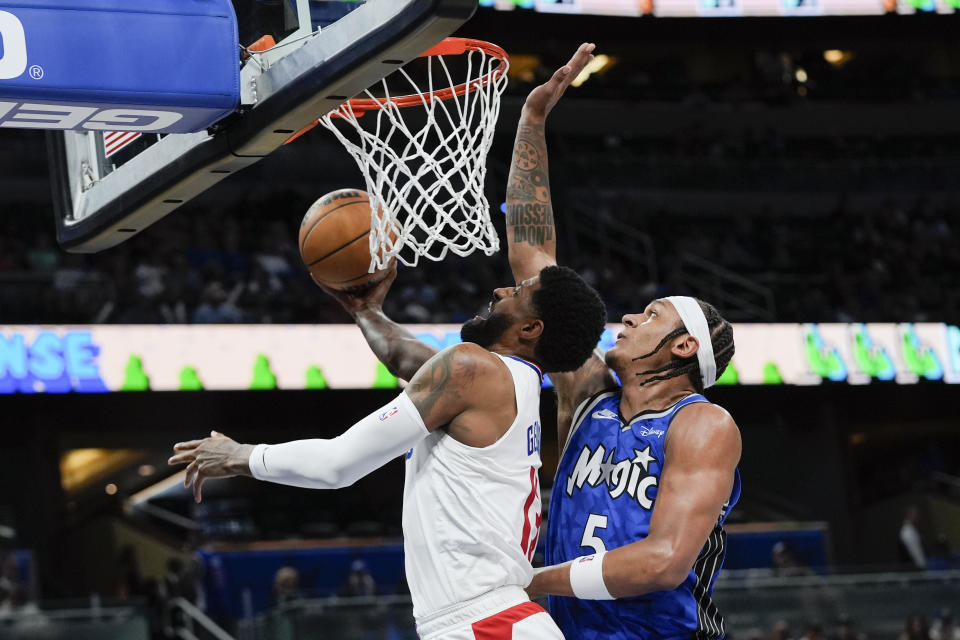 Los Angeles Clippers forward Paul George, left, gets by Orlando Magic forward Paolo Banchero (5) for a basket during the second half of an NBA basketball game, Friday, March 29, 2024, in Orlando, Fla. (AP Photo/John Raoux)