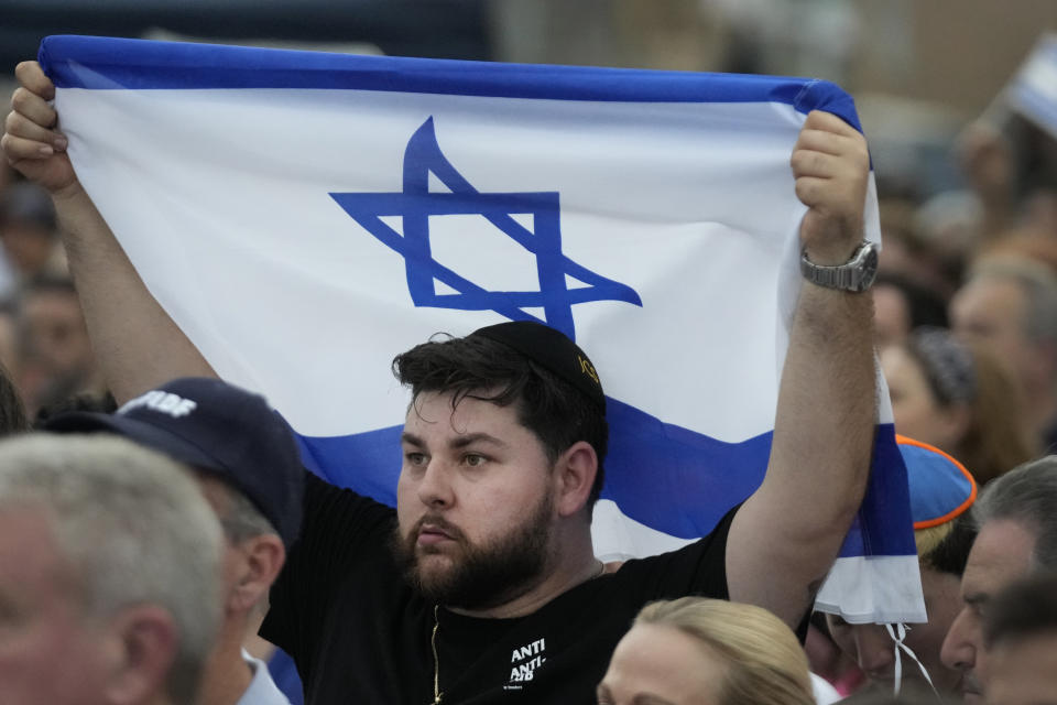 FILE - A man holds up an Israeli flag as he attends a rally in support of Israel, at the Holocaust Memorial Miami Beach, Oct. 10, 2023, in Miami Beach, Fla. An estimated 525,000 Jews live in Miami's metropolitan area according to the American Jewish Population Project at Brandeis University. In South Florida, rabbis and community leaders are pushing their congregations to call their lawmakers and insist they back Israel as it ramps up its offensive. (AP Photo/Wilfredo Lee, File)