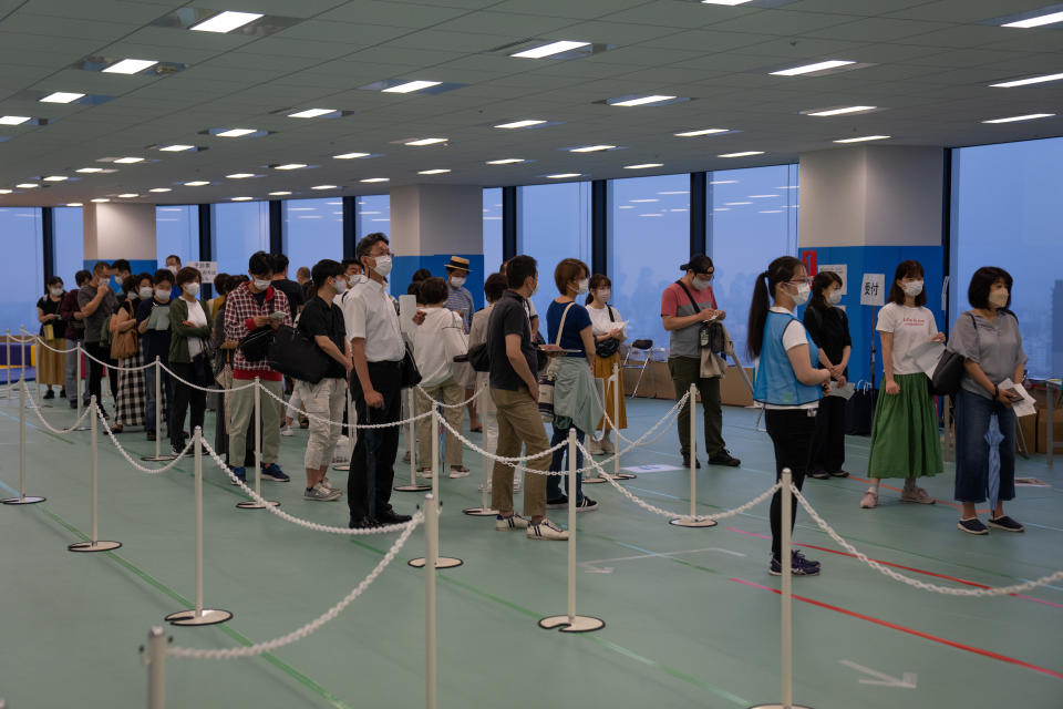 People line up to register for a dose of the Moderna vaccine on June 30 in Tokyo. The Japanese government has begun an after-hours vaccination campaign as it expands its coronavirus inoculation drive to include younger people. (Carl Court/Getty Images)