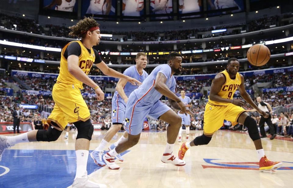 Los Angeles Clippers's DeAndre Jordan, center, goes after a loose ball against Cleveland Cavaliers's Anderson Varejao, left, and Luol Deng during the first half of an NBA basketball game on Sunday, March 16, 2014, in Los Angeles. (AP Photo/Jae C. Hong)