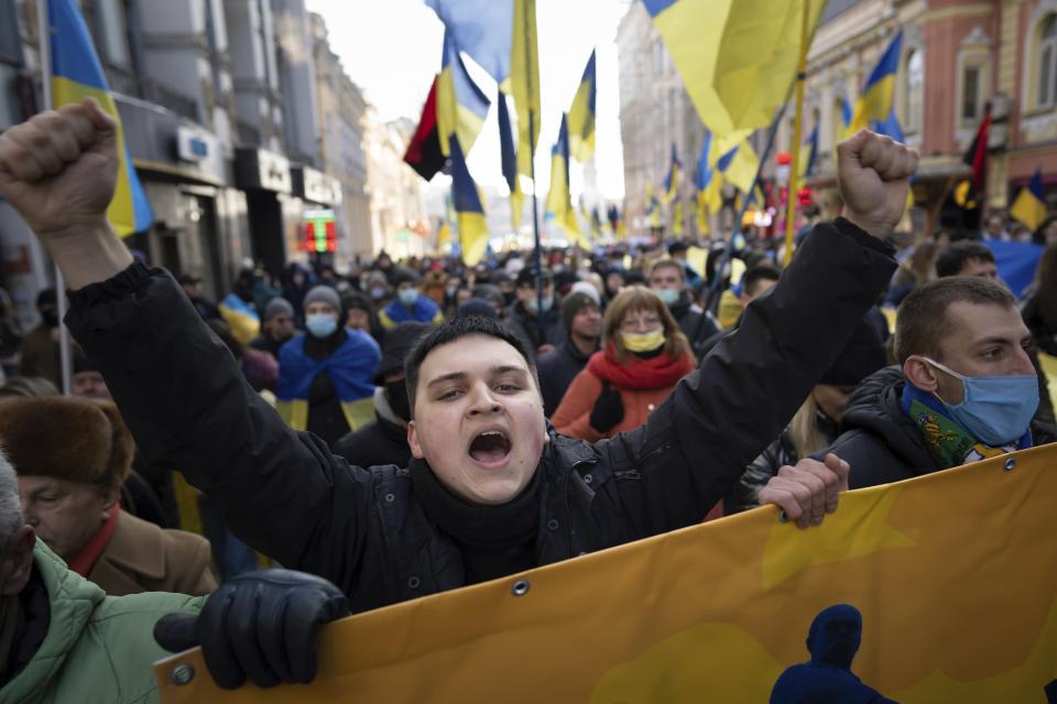 Demonstrators with Ukrainian national flags, one of them shouts, rally against Russian aggression in the center of Kharkiv, Ukraine's second-largest city, Saturday, Feb. 5, 2022, just 40 kilometers (25 miles) from some of the tens of thousands of Russian troops massed at the border of Ukraine. After weeks of talks in various diplomatic formats have led to no major concessions by Russia and the U.S., it's unclear how much impact the trips will have. But Ukraine's Foreign Minister Dmytro Kuleba said Friday that "top-level visits seriously reduce challenges in the sphere of security and upset the Kremlin's plans." (AP Photo/Evgeniy Maloletka)