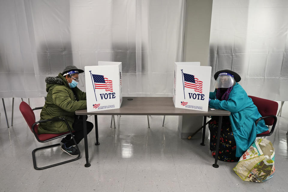 FILE - In this Oct. 6, 2020, file photo two voters fill out ballots during early voting at the Cuyahoga County Board of Elections in Cleveland. Courts nationwide have seen a flurry of litigation over the 2020 presidential election as both major parties jockey for every advantage. President Donald Trump and Democrat Joe Biden’s campaigns are assembling armies of powerful lawyers. (AP Photo/Tony Dejak, File)