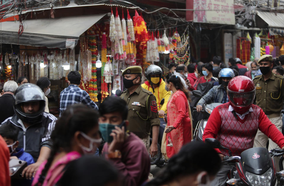 Indian policemen wearing face masks as a precautionary measure against the coronavirus walk in a market during Diwali, the Hindu festival of lights, in Jammu, India, Saturday, Nov. 14, 2020. (AP Photo/ Channi Anand)