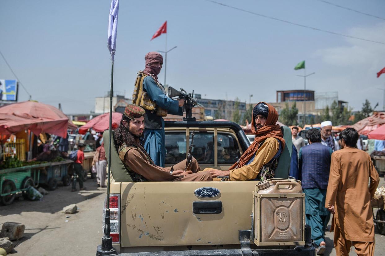 Taliban fighters on a pick-up truck move around a market area, flocked with local Afghan people at the Kote Sangi area of Kabul on August 17, 2021, after Taliban seized control of the capital following the collapse of the Afghan government (AFP via Getty Images)