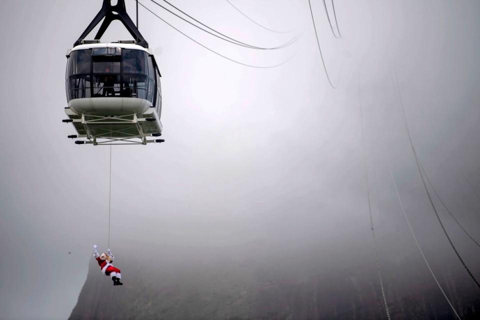 <div class="inline-image__caption"><p>A man disguised as Santa Claus, suspended from the Sugar Loaf's Cable car, waved at visitors upon arrival to the Sugar Loaf mountain, in Rio de Janeiro, Brazil, on December 05, 2020.</p></div> <div class="inline-image__credit">Mauro Pimentel/Getty</div>