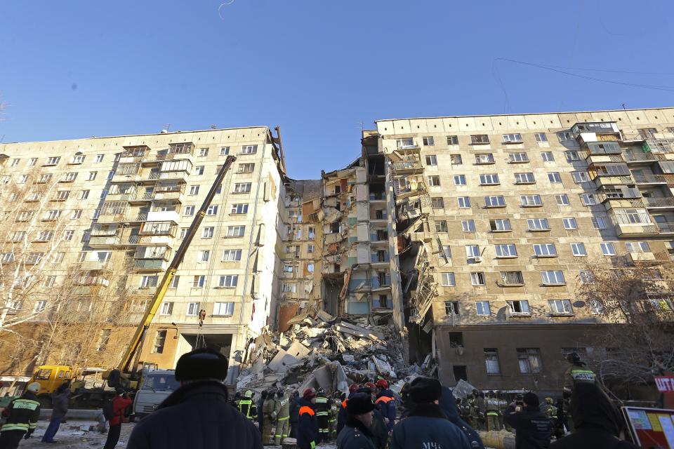 Emergency Situations employees working at the scene of a collapsed apartment building in Magnitogorsk, a city of 400,000 people, about 1,400 kilometers (870 miles) southeast of Moscow, Russia, Monday, Dec. 31, 2018. Russian emergency officials say that at least four people have died after sections of the apartment building collapsed after an apparent gas explosion in the Ural Mountains region. (AP Photo/Maxim Shmakov)