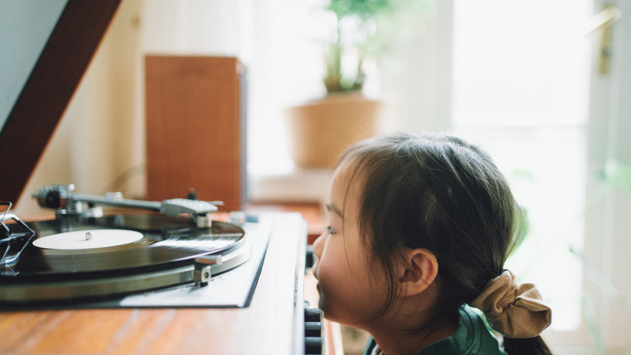  Child watching a vinyl record played on a turntable. 