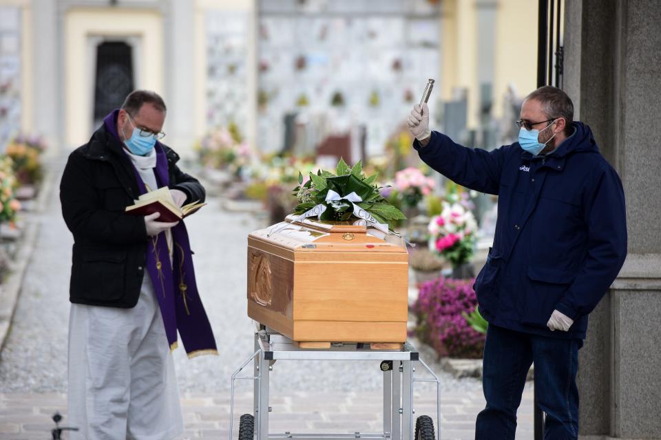 Uno de los portadores del féretro ayuda al sacerdote durante el funeral de una persona fallecida en la crisis del coronavirus en Bolgare. (PIERO CRUCIATTI/AFP via Getty Images)