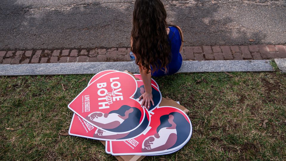 A woman rests next to anti-abortion posters in front of the US Supreme Court on June 24, 2022. - Nathan Howard/Getty Images/File