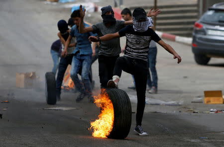 A Palestinian protester rolls a burning tire during clashes with Israeli troops in Hebron, in the occupied West Bank April 20, 2018. REUTERS/Mussa Qawasma