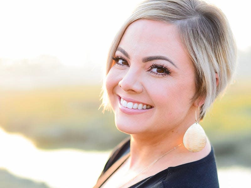 Amanda C. Riley with blonde hair and a Black shirt smiling.