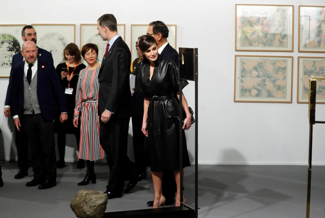 La reina junto a su esposo Felipe VI y sus invitados, mientras observa una de las obras. EFE