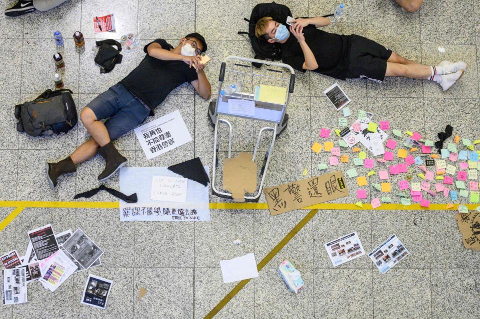 Protesters rest among signs at Hong Kong's International airport during a protest against the police brutality and the controversial extradition bill.