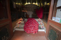 A flamenco dress, dancing shoes, a guitar and candles are laid out in the entrance of the Villa Rosa Tablao flamenco venue during a protest in Madrid, Spain, Thursday March 4, 2021. The National Association of Tablaos protested outside the mythical Villa Rosa Tablao which has been forced to close permanently due to the covid pandemic. (AP Photo/Paul White)