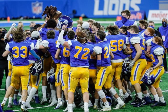 Grand Rapids Catholic Central players celebrate with the championship trophy after defeating Frankenmuth at the MHSAA Division 5 final at Ford Field, Saturday, Jan. 23, 2021.