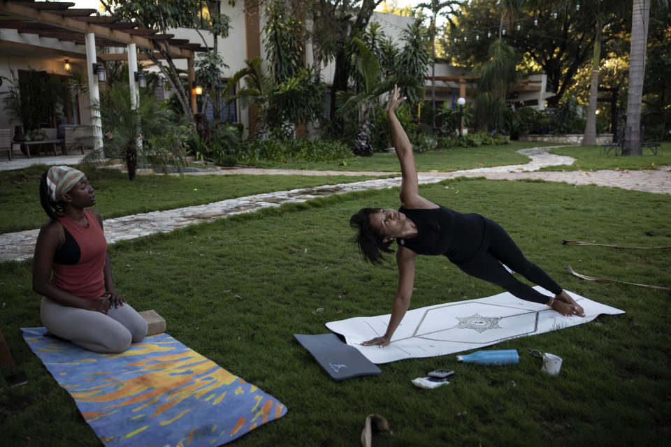 Businesswoman Magalie Dresse does a side plank during her morning yoga routine in the garden of her home in Port-au-Prince, Haiti, Tuesday, Sept. 14, 2021. Dresse lives in an elegant home in the heart of the capital, where she does yoga in the morning. "I need the strength to go out there and handle what I'm going to find, which is not going to be positive." says Dresse. (AP Photo/Rodrigo Abd)