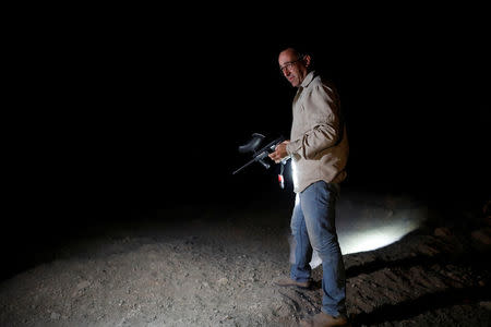 David Greenbaum, manager of Ein Gedi nature reserve, holds a paintball rifle during a late-night patrol to distance wolves in Ein Gedi nature reserve, near the Dead Sea, Israel September 27, 2017. REUTERS/Ronen Zvulun