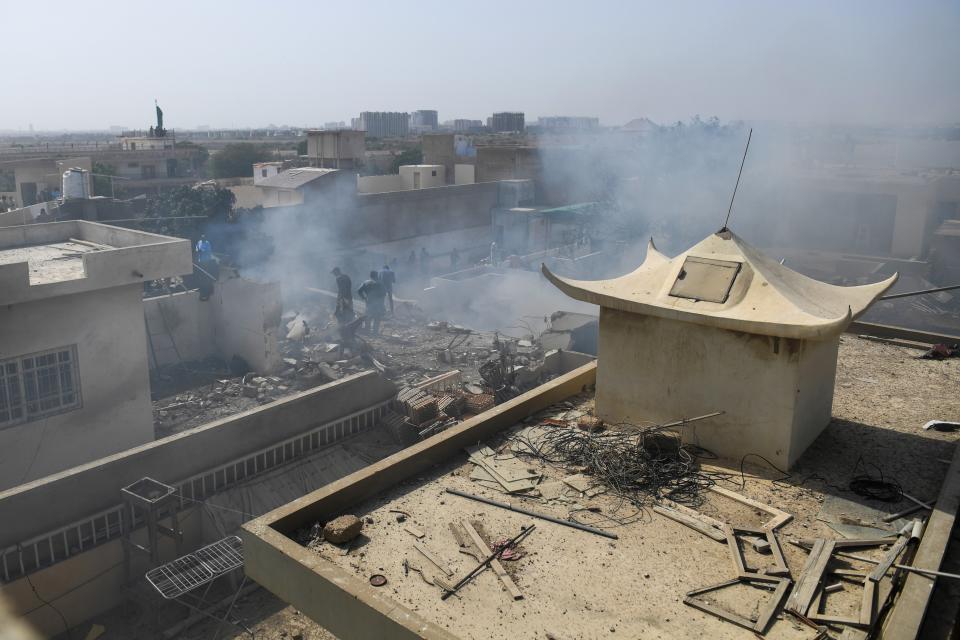 Rescue workers gather at the site after a Pakistan International Airlines flight crashed in a residential neighbourhood in Karachi on May 22, 2020. - A Pakistan passenger plane with more than 100 people believed to be on board crashed in the southern city of Karachi on May 22, the country's aviation authority said. (Photo by Asif HASSAN / AFP) (Photo by ASIF HASSAN/AFP via Getty Images)