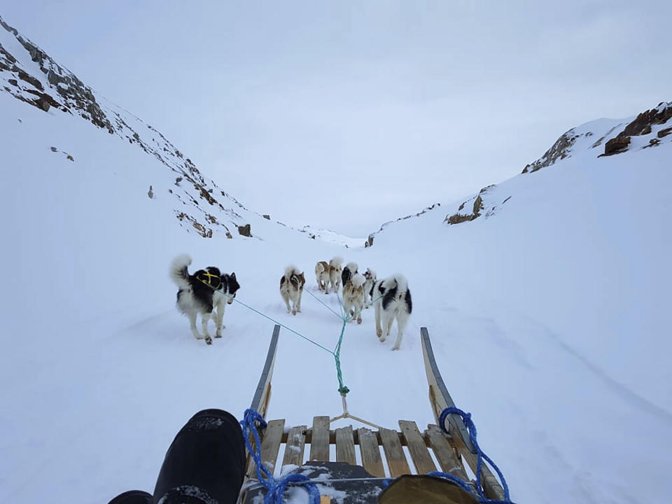 In this Feb. 11, 2021, photo, provided by Lars Rasmussen, dogs pull him on a sled in the eastern Greenland town of Tasiilaq. “The warm weather makes dog sledding and driving on snow scooters a bit of a hassle,” Rasmussen said. (Lars Rasmussen via AP)