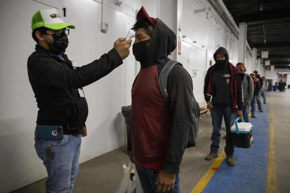 KING CITY, CA - APRIL 28: Migrant farm laborers with Fresh Harvest working with an H-2A visa have their temperature checked and are asked questions about their health before boarding the bus to their shift, in the company living quarters on April 28, 2020 in King City, California.  Good accommodations for farm labor is vital but difficult during the coronavirus pandemic. Fresh Harvest houses over 300 laborers in their self-contained King City facility. The laborers are given masks and gloves, and practice social distancing while inside. If anyone experiences health irregularities, they are immediately isolated in different housing and monitored at least twice a day. Medical care from the county is available if further symptoms develop. Accommodations are expensive and difficult to procure for farm labor. Many growers and packers use motels, houses that they purchase and warehouse-style housing. Fresh Harvest is the one of the largest employers of people using the H-2A temporary agricultural worker visa for labor, harvesting and staffing in the United States. The company is implementing strict health and safety initiatives for their workers during the coronavirus pandemic and are trying a number of new techniques to enhance safety in the field as well as in work accommodations. Employees have their temperature taken daily and are also asked a series of questions about how they feel. Despite current record unemployment rates in the U.S. due to COVID-19-related layoffs, there have been few applications to do this kind of work despite extensive mandatory advertising by companies such as Fresh Harvest. (Photo by Brent Stirton/Getty Images)