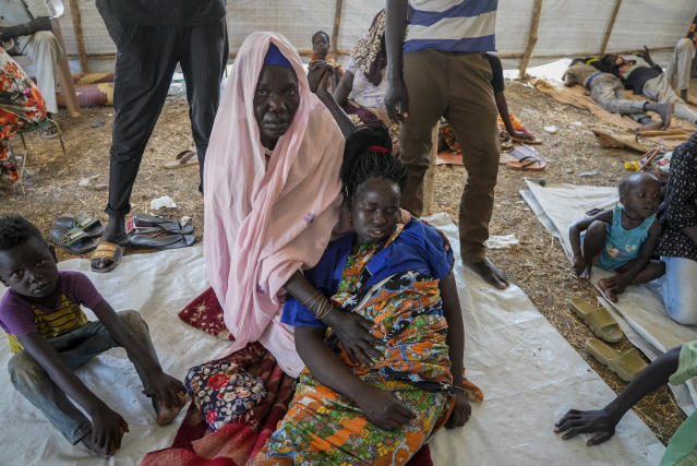 A woman who crossed from Sudan to South Sudan holds another, who is sick, at a makeshift clinic at the Joda border crossing in South Sudan Tuesday, May 16, 2023. Tens of thousands of South Sudanese are flocking home from neighboring Sudan, which erupted in violence last month. (AP Photo/Sam Mednick)
