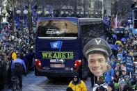 A photo of Seattle Seahawks quarterback Russell Wilson is held up by fans lining the street during the Super Bowl champions parade on Wednesday, Feb. 5, 2014, in Seattle. The Seahawks beat the Denver Broncos 43-8 in NFL football's Super Bowl XLVIII on Sunday. (AP Photo/Ted S. Warren)