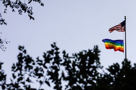 FILE PHOTO: A rainbow pride flag is seen with the U.S. national flag at a building ahead of the 50th anniversary of the Stonewall riot, in New York