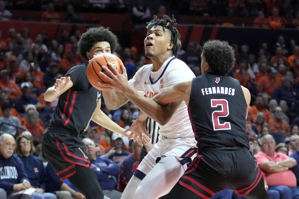 Illinois' Terrence Shannon Jr., center, drives to the basket between Rutgers' Derek Simpson, left, and Noah Fernandes during the first half of an NCAA college basketball game Sunday, Jan. 21, 2024, in Champaign, Ill. (AP Photo/Charles Rex Arbogast)