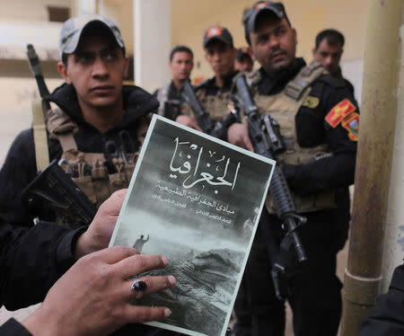 In Iraqi special forces soldier holds a school book issued by Islamic State fighters in a school in Mosul, Iraq, November 16, 2016. REUTERS/Goran Tomasevic