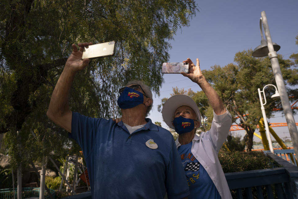 Allan Ansdell Sr. and wife, Yvonne, parents of Allan Ansdell Jr, owner and president of Adventure City amusement park, use their smartphones to record their great-grandchildren riding a roller coaster at the amusement park on the day of reopening in Anaheim, Calif., Friday, April 16, 2021. The family-run amusement park that had been shut since March last year because of the coronavirus pandemic reopened on April 16. (AP Photo/Jae C. Hong)