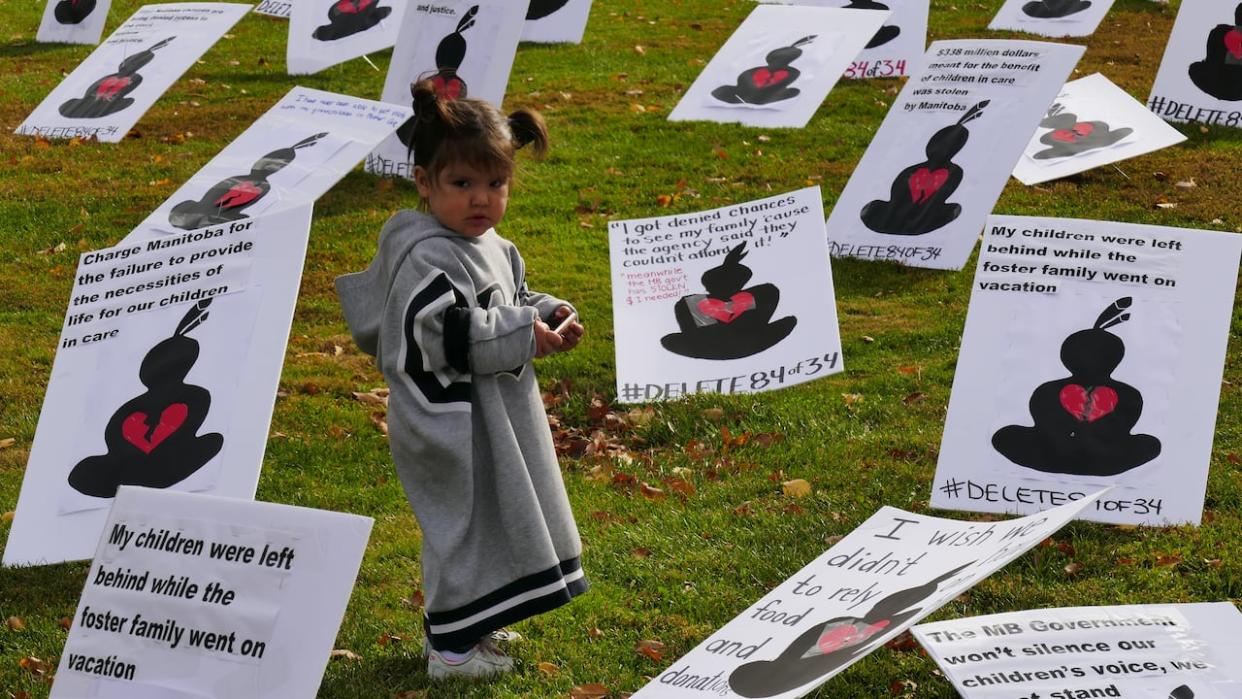 In 2020, a child among along signs condemning the government for holding onto hundreds of millions of dollars in money that critics felt should have been re-directed to CFS agencies and authorities. The government has reached a settlement in 2024 to settle three class-action lawsuits.  (Trevor Brine/CBC - image credit)