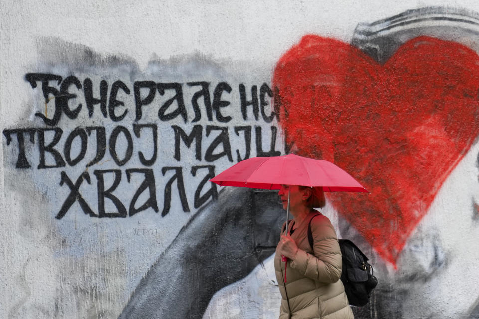 A woman walks by a mural of former Bosnian Serb military chief Ratko Mladic vandalized with red paint in Belgrade, Serbia, Monday, May 8, 2023. Mladic is serving a life sentence for genocide during the 1992-95 War in Bosnia but whom many Serbs still consider a hero. (AP Photo/Darko Vojinovic)