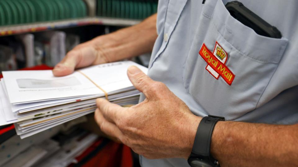 A Royal Mail worker holding a bunch of letters