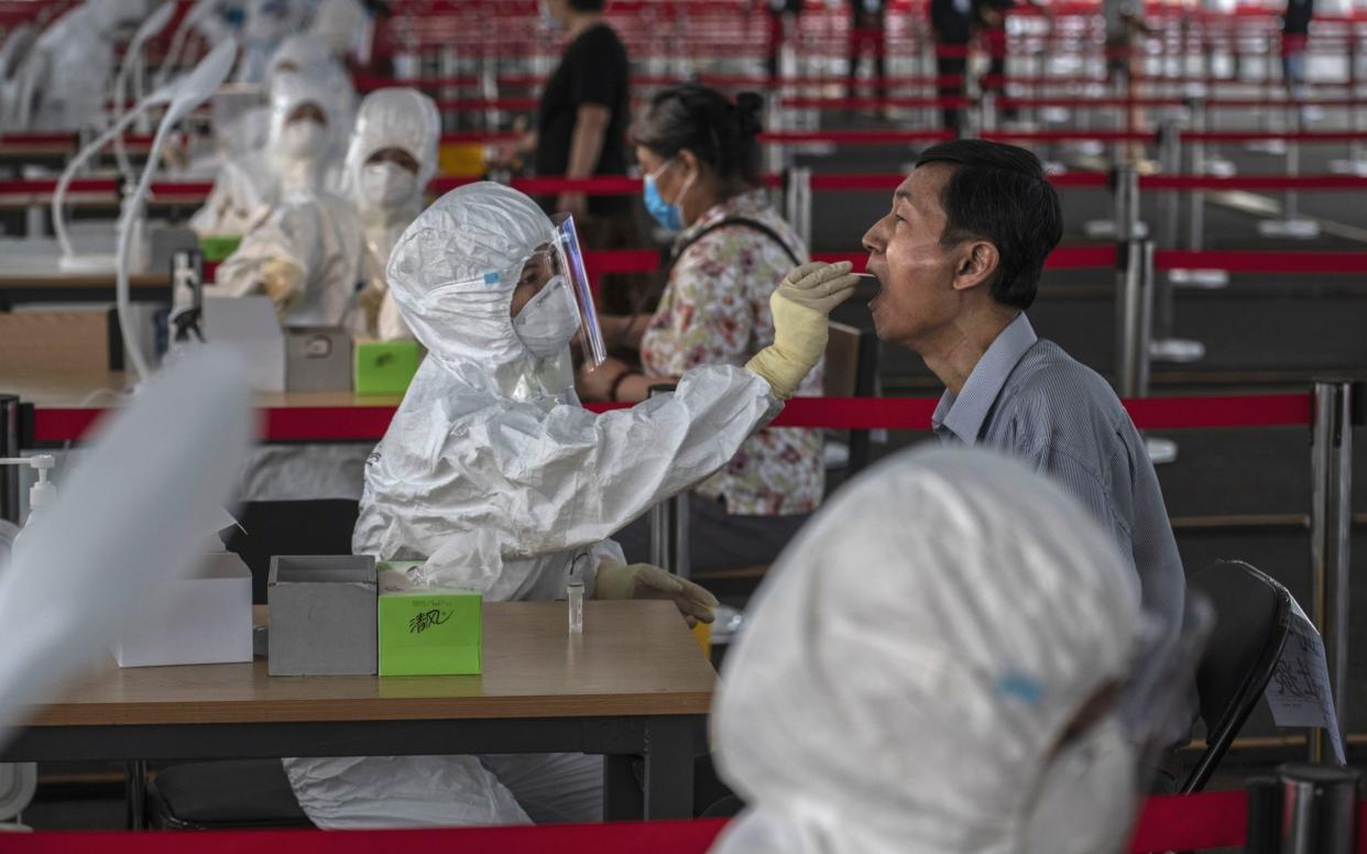 A Chinese epidemic control worker wears a protective suit as she performs a nucleic acid swab test for COVID-19 on a man at a government testing site in Xicheng District, Beijing - Kevin Frayer/Getty Images