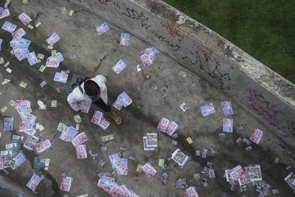 A woman walks on a path littered with electoral leaflets in the Rocinha favela in Rio de Janeiro, Brazil, Sunday, Oct. 7, 2018. Brazilians choose among 13 candidates for president Sunday in one of the most unpredictable and divisive elections in decades. If no one gets a majority in the first round, the top two candidates will compete in a runoff. (AP Photo/Ricardo Borges)