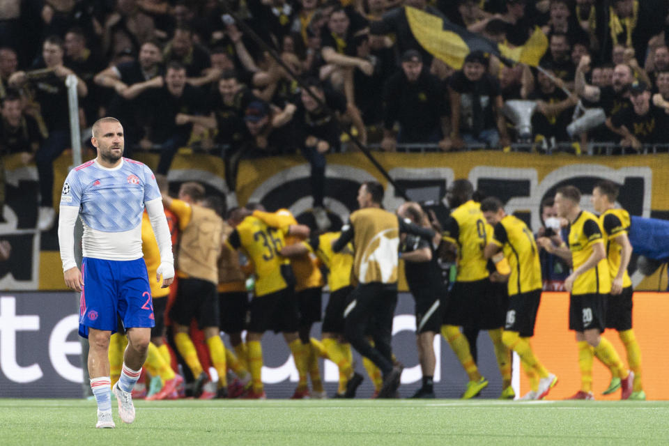 Manchester's Luke Shaw looks dejected as Young Boys celebrate after scoring during of the Champions League group F soccer match between BSC Young Boys and Manchester United, at the Wankdorf stadium in Bern, Switzerland, Tuesday, Sept. 14, 2021. (Alessandro della Valle/Keystone via AP)