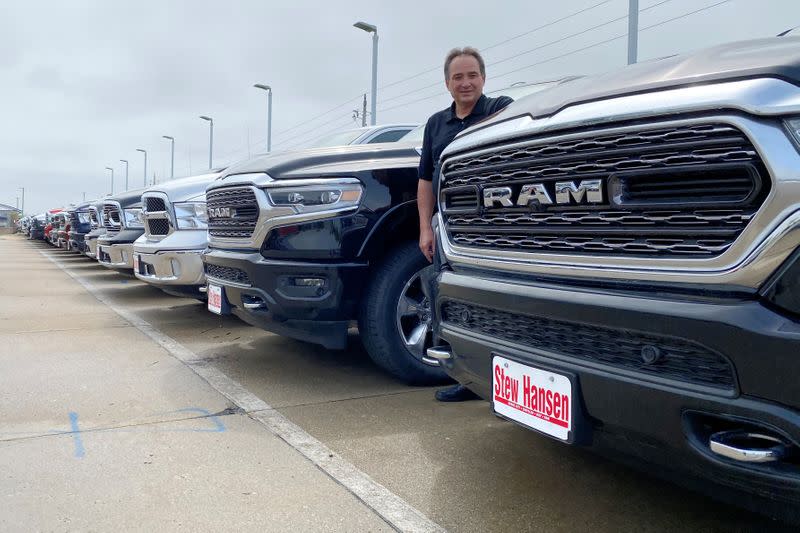 Jerry Bill, general manager of Stew Hansen Chrysler Dodge Jeep Ram, poses among a line of Ram trucks in Urbandale