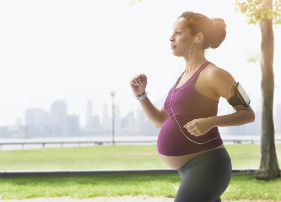 A pregnant woman running outside whilst listening to music