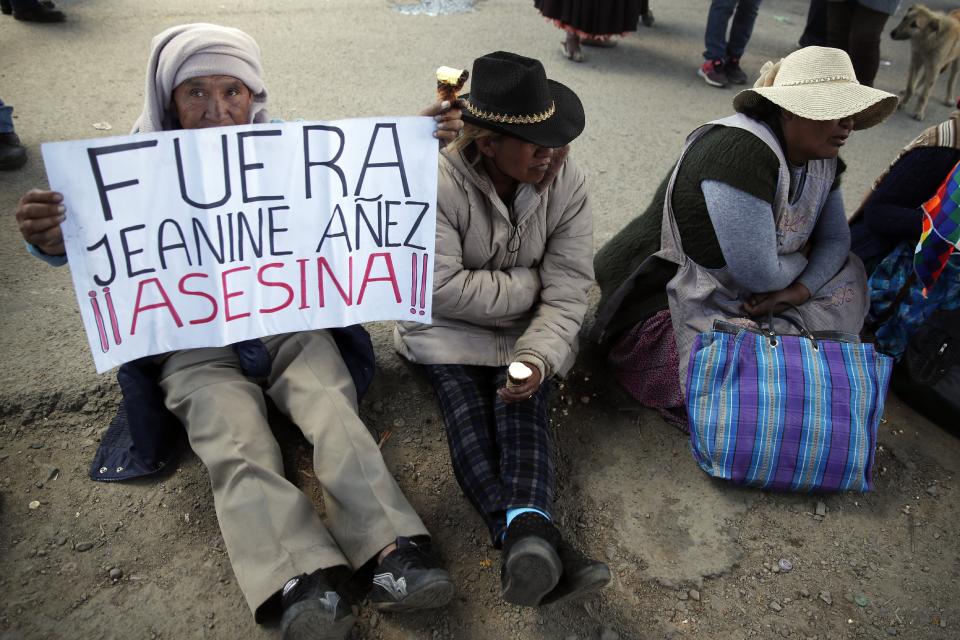 A supporter of former President Evo Morales holds a sign with a handwritten message that reads in Spanish: "Get out Jeanine Añez, assassin!!," in reference to Bolivia's interim president, during a protest at a blocked highway in El Alto, on the outskirts of La Paz, Bolivia, Wednesday, Nov. 20, 2019. Bolivia has been in a state of turbulence since a disputed Oct. 20 vote. Morales resigned Nov. 10, but his supporters oppose the interim government that took his place. (AP Photo/Natacha Pisarenko)
