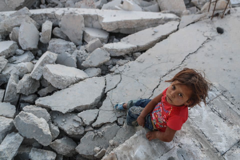 A child sits amongst the rubble after another airstrike on 26 June, 2017. Photo: AAP